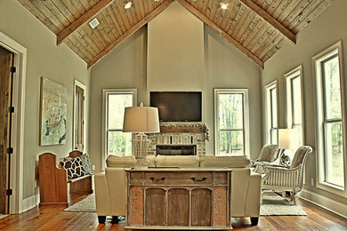 Inspiration for a large rustic enclosed medium tone wood floor and brown floor family room remodel in Jackson with gray walls, a standard fireplace, a wall-mounted tv and a brick fireplace