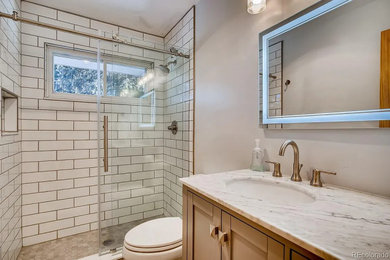 Mid-sized farmhouse 3/4 white tile and subway tile ceramic tile, gray floor and single-sink sliding shower door photo in Other with shaker cabinets, gray cabinets, a two-piece toilet, gray walls, an undermount sink, marble countertops, white countertops, a niche and a freestanding vanity