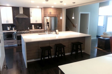 This is an example of a mid-sized contemporary single-wall open plan kitchen in Calgary with an undermount sink, flat-panel cabinets, light wood cabinets, solid surface benchtops, blue splashback, mosaic tile splashback, stainless steel appliances, dark hardwood floors and with island.