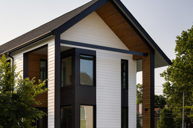 Mid-sized minimalist white three-story concrete fiberboard and clapboard exterior home photo in Kansas City with a shingle roof and a black roof