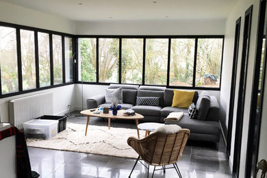 This is an example of a small modern open concept living room in Rennes with white walls, ceramic floors, a concealed tv and grey floor.