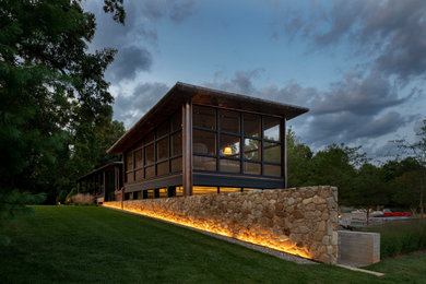 Huge minimalist beige two-story stone house exterior photo with a shed roof and a metal roof