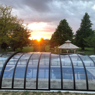 Immagine di una grande privacy sulla terrazza chic dietro casa e a piano terra con un tetto a sbalzo e parapetto in vetro
