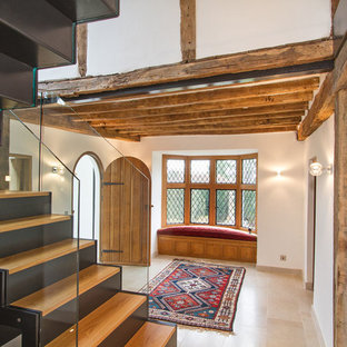 Aménagement d'un grand hall d'entrée éclectique avec un mur blanc, un sol en calcaire, une porte simple, une porte en bois brun et un sol beige.