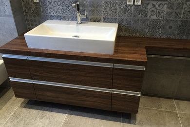 Mittelgroßes Modernes Badezimmer mit flächenbündigen Schrankfronten, braunen Schränken, grauen Fliesen, Waschtisch aus Holz, brauner Waschtischplatte, Einzelwaschbecken und schwebendem Waschtisch in Sonstige