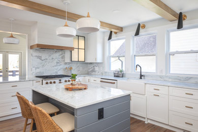 Kitchen - mid-sized eclectic medium tone wood floor, brown floor and exposed beam kitchen idea in Raleigh with a farmhouse sink, shaker cabinets, white cabinets, quartzite countertops, white backsplash, quartz backsplash, white appliances, an island and white countertops