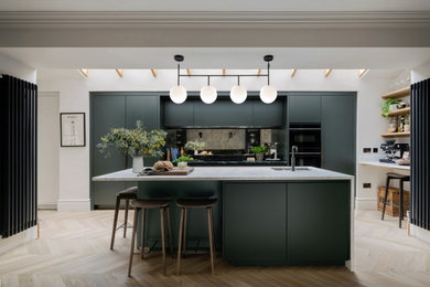 Inspiration for a medium sized contemporary galley open plan kitchen in London with a built-in sink, flat-panel cabinets, green cabinets, marble worktops, metallic splashback, glass sheet splashback, stainless steel appliances, an island and white worktops.
