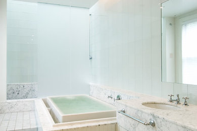 Example of a large minimalist master white tile and ceramic tile porcelain tile and gray floor doorless shower design in Other with a drop-in sink, white cabinets, marble countertops, a hot tub, white walls and flat-panel cabinets