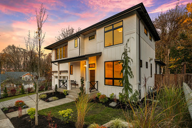 Photo of a large contemporary three-storey white house exterior in Seattle with wood siding and a flat roof.