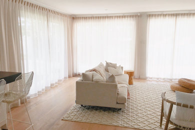 This is an example of a contemporary living room with white walls and light hardwood floors.