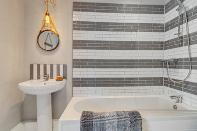 Photo of a mid-sized beach style master bathroom in Cheshire with a corner tub, a shower/bathtub combo, a wall-mount toilet, gray tile, terra-cotta tile, grey walls, painted wood floors, a pedestal sink, white floor, a hinged shower door, a shower seat, a single vanity, a freestanding vanity and planked wall panelling.