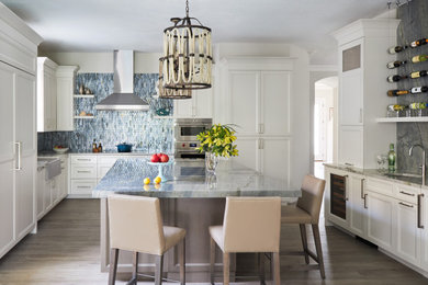 Inspiration for a large coastal l-shaped porcelain tile and gray floor kitchen remodel in Other with a farmhouse sink, recessed-panel cabinets, white cabinets, quartzite countertops, multicolored backsplash, glass tile backsplash, stainless steel appliances, an island and blue countertops