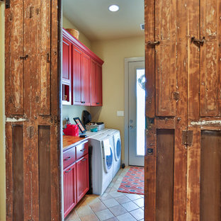 Medium sized farmhouse utility room in Austin with red cabinets, wood worktops, ceramic flooring, a side by side washer and dryer, recessed-panel cabinets and beige walls.