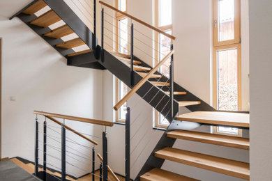 Foto de escalera contemporánea con escalones de madera y barandilla de metal