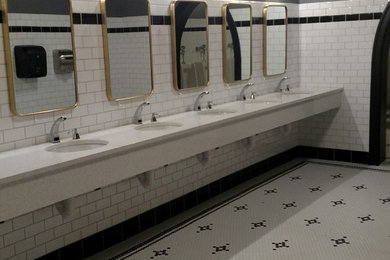 Photo of a traditional bathroom in Detroit with a wall-mount toilet, black and white tile, ceramic tile, porcelain floors, quartzite benchtops and white benchtops.