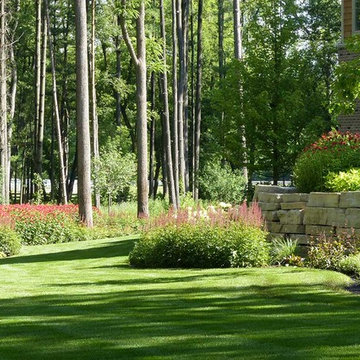 Large sweeping beds of bee balm and astilbe with stone retaining wall