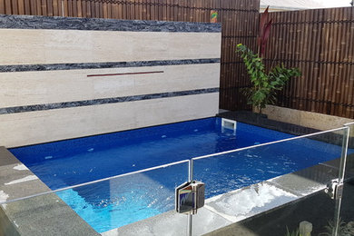 Modelo de piscina con fuente elevada contemporánea pequeña rectangular en patio con adoquines de piedra natural
