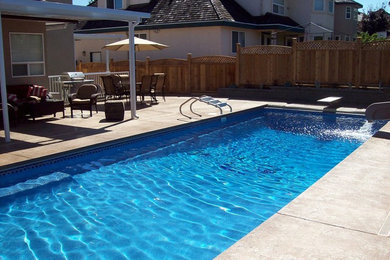 Imagen de piscina con tobogán de estilo americano de tamaño medio rectangular en patio trasero con losas de hormigón
