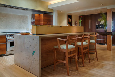 Open concept kitchen - mid-sized contemporary l-shaped light wood floor open concept kitchen idea in San Francisco with a farmhouse sink, flat-panel cabinets, medium tone wood cabinets, concrete countertops, white backsplash, ceramic backsplash, stainless steel appliances and an island