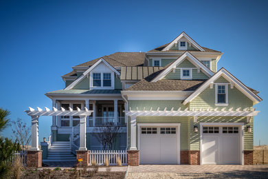 Large beach style green two-story wood exterior home photo in New York with a shingle roof