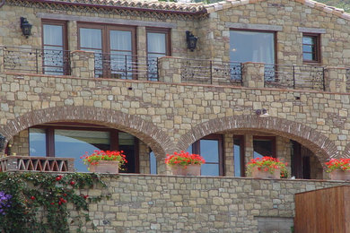 Mid-sized mediterranean beige two-story stone flat roof idea in Los Angeles