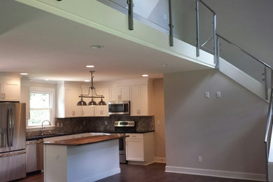 Example of a mid-sized minimalist l-shaped medium tone wood floor eat-in kitchen design in Nashville with a single-bowl sink, shaker cabinets, white cabinets, granite countertops, gray backsplash, stone tile backsplash, stainless steel appliances and an island