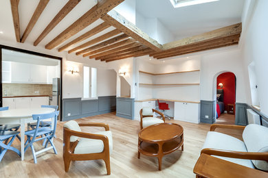 Réalisation d'un grand salon design ouvert avec une bibliothèque ou un coin lecture, un mur blanc, parquet clair, aucune cheminée et un sol marron.