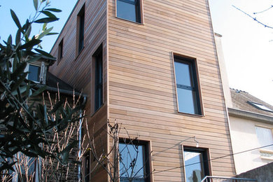 Réalisation d'une grande façade de maison beige design en bois à deux étages et plus.