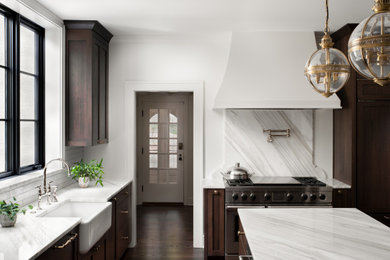 Example of a large transitional dark wood floor and brown floor eat-in kitchen design in Kansas City with a farmhouse sink, recessed-panel cabinets, dark wood cabinets, marble countertops, white backsplash, ceramic backsplash, paneled appliances, an island and white countertops