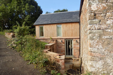 Medium sized rural two floor detached house in Other with wood cladding, a pitched roof and a tiled roof.