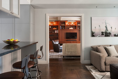 Example of a large trendy open concept dark wood floor and brown floor family room design in New York with beige walls, no fireplace and a wall-mounted tv