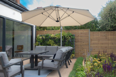 This is an example of a medium sized modern back patio in London with a living wall, tiled flooring and no cover.
