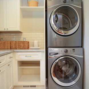 Foto de cuarto de lavado en L, tradicional, pequeño, con puertas de armario blancas, encimera de mármol y lavadora y secadora apiladas