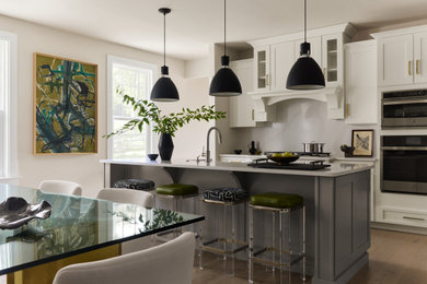 Eat-in kitchen - transitional galley medium tone wood floor and brown floor eat-in kitchen idea in Philadelphia with shaker cabinets, white cabinets, white backsplash, stainless steel appliances, an island and white countertops