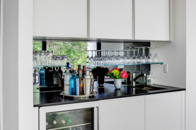 Home bar - home bar idea in Boston with white cabinets, granite countertops, mirror backsplash and black countertops