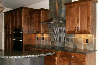 Kitchen - mid-sized contemporary galley dark wood floor kitchen idea in Other with flat-panel cabinets, brown cabinets, granite countertops, multicolored backsplash, porcelain backsplash, stainless steel appliances and an island