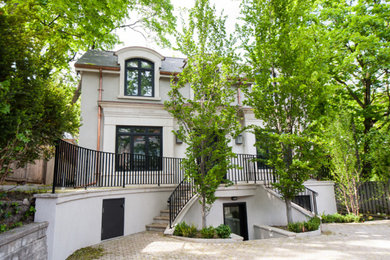 Large contemporary white split-level stucco exterior home idea in Toronto with a hip roof