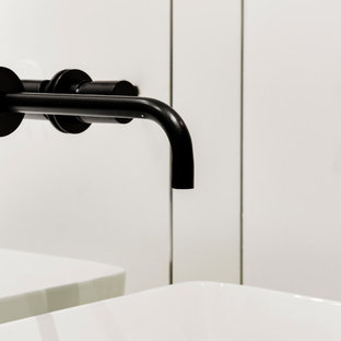 Diseño de cuarto de baño principal, contemporáneo, de tamaño medio, con armarios con paneles lisos, puertas de armario negras, baldosas y/o azulejos blancos, baldosas y/o azulejos con efecto espejo, paredes blancas, suelo de azulejos de cemento, lavabo sobreencimera, encimera de cuarcita, suelo negro, encimeras blancas, bañera encastrada sin remate, combinación de ducha y bañera y ducha con puerta con bisagras