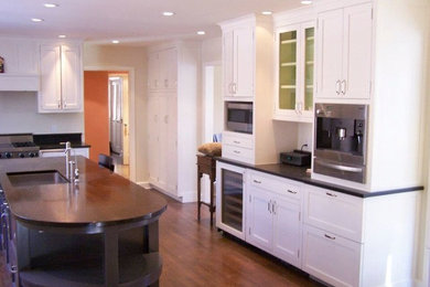 Inspiration for a timeless l-shaped dark wood floor eat-in kitchen remodel in New York with an undermount sink, shaker cabinets, white cabinets, wood countertops, stainless steel appliances and an island