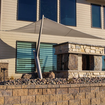 Towering Stone Fire Place Next to Foundation Wall, Softscapes, and Sun Sails