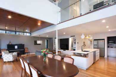 Large modern open plan dining in Brisbane with grey walls and medium hardwood floors.