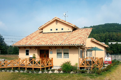 Mid-sized two-storey orange house exterior in Other with a gable roof and a tile roof.