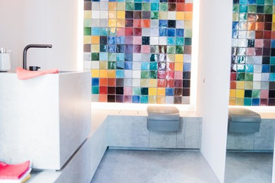 Mittelgroße Moderne Gästetoilette mit Betonboden, farbigen Fliesen, Glasfliesen, weißer Wandfarbe, Sockelwaschbecken, Beton-Waschbecken/Waschtisch, grauem Boden und grauer Waschtischplatte in München