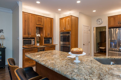 Large elegant l-shaped porcelain tile, white floor and tray ceiling eat-in kitchen photo in Richmond with a farmhouse sink, flat-panel cabinets, medium tone wood cabinets, granite countertops, multicolored backsplash, granite backsplash, stainless steel appliances, a peninsula and multicolored countertops