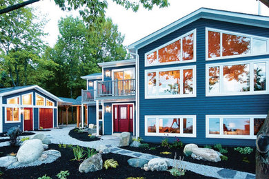 Cette image montre une grande façade de maison bleue marine à un étage avec un toit gris et un toit en shingle.
