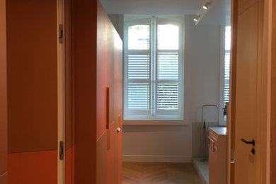 Modelo de armario vestidor unisex contemporáneo extra grande con armarios con paneles lisos y suelo de madera clara