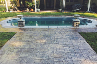 Photo of a large traditional back custom shaped swimming pool in Raleigh with stamped concrete.