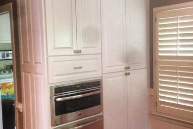 Example of a mid-sized kitchen pantry design in Richmond with raised-panel cabinets, white cabinets and stainless steel appliances
