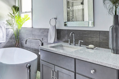 Minimalist master gray tile porcelain tile and gray floor bathroom photo in Other with recessed-panel cabinets, gray cabinets, a one-piece toilet, gray walls, an undermount sink, quartz countertops, a hinged shower door and white countertops