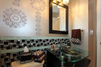 Photo of a small transitional powder room in Other with a vessel sink, glass benchtops, a one-piece toilet, multi-coloured tile, porcelain floors and dark wood cabinets.